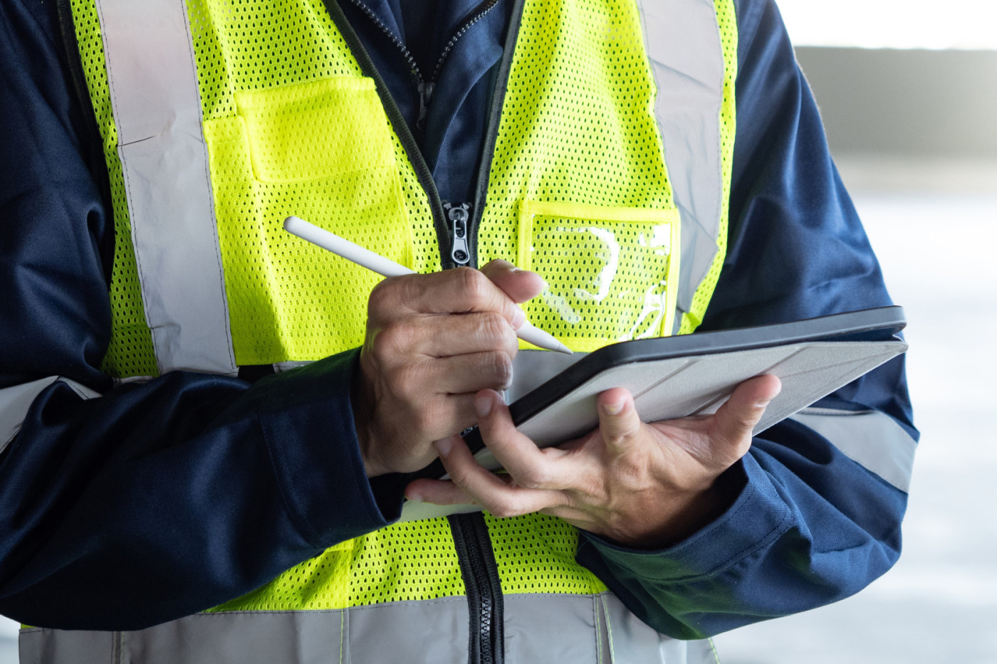 Ein Bauinspektor überprüft mit einem digitalen Tablet das Sicherheits- und Schutzsystem im Gebäude. Arbeiter in Warnweste bei der Wartungsinspektion eines Gebäudes.