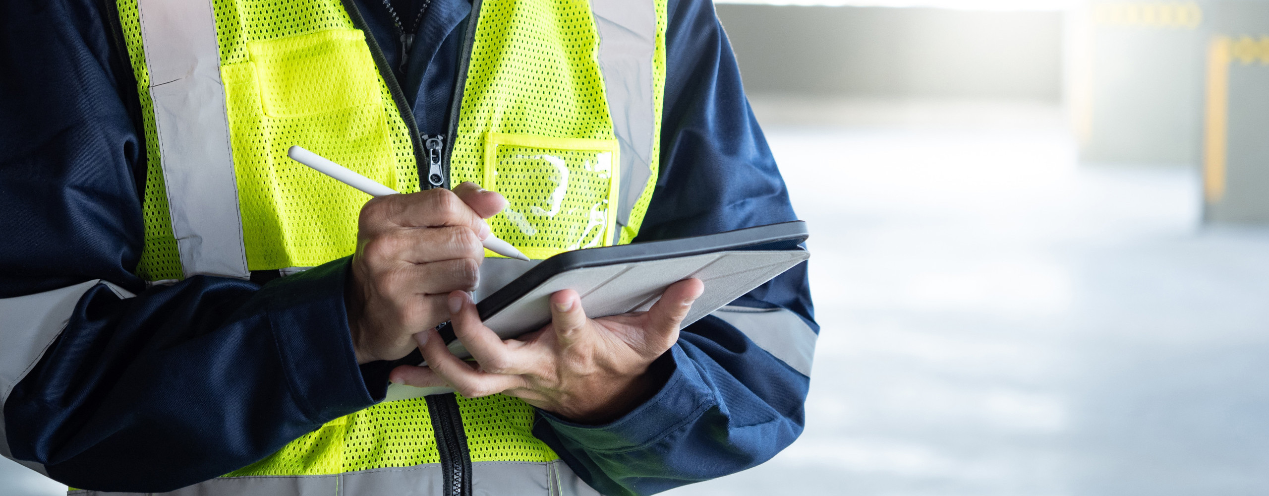 Ein Bauinspektor überprüft mit einem digitalen Tablet das Sicherheits- und Schutzsystem im Gebäude. Arbeiter in Warnweste bei der Wartungsinspektion eines Gebäudes.