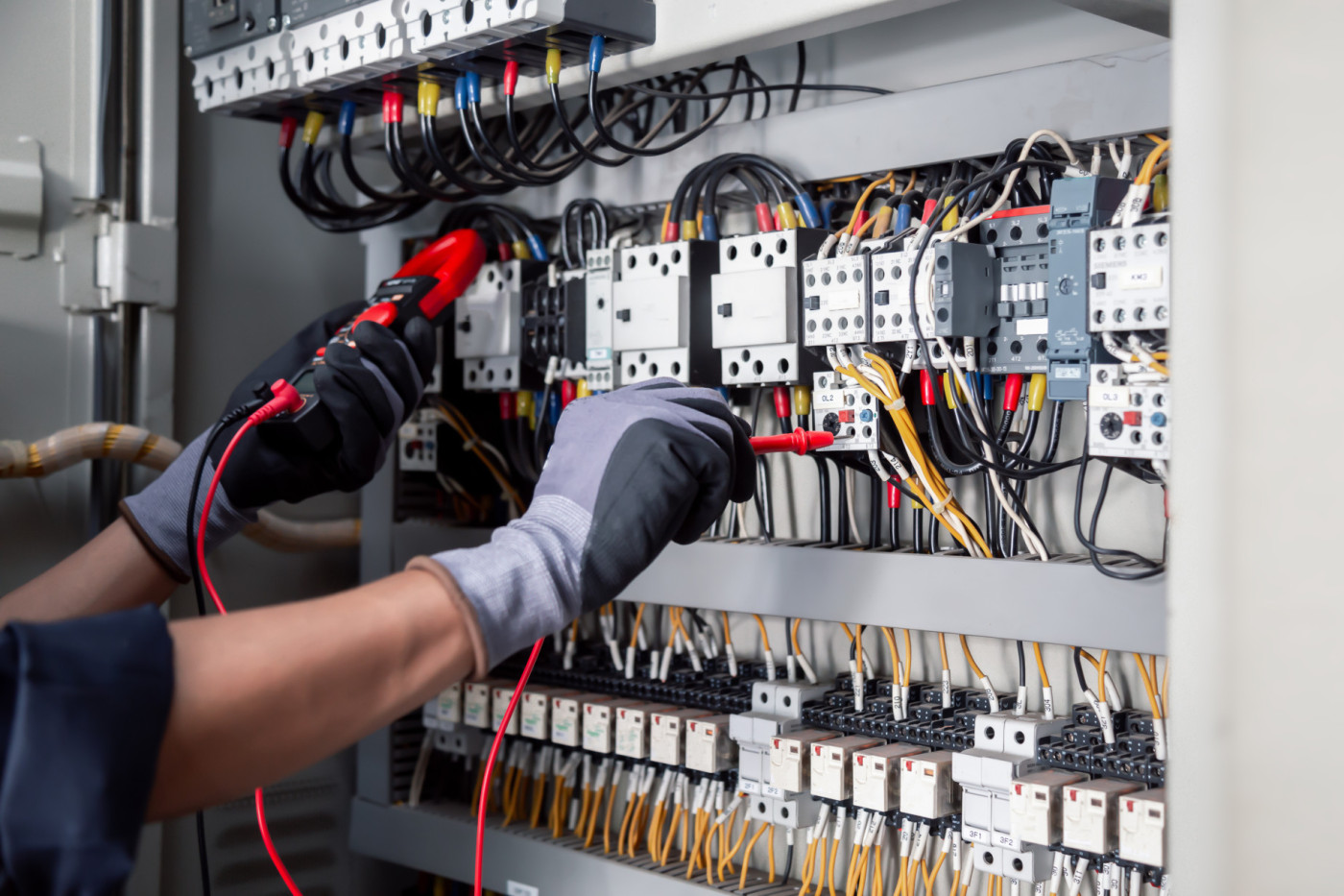 Elektrizitäts- und Elektro-Wartungsservice: Elektrische Prüfungen von industriellen Stromkreisen mit einem Multimeter in der Steuerklemmenbox.