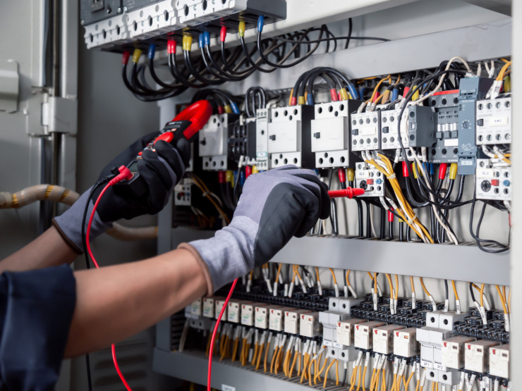 Elektrizitäts- und Elektro-Wartungsservice: Elektrische Prüfungen von industriellen Stromkreisen mit einem Multimeter in der Steuerklemmenbox.
